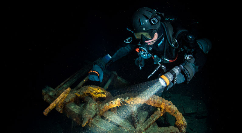 Scuba diver exploring a wreck with high lumen diving torch